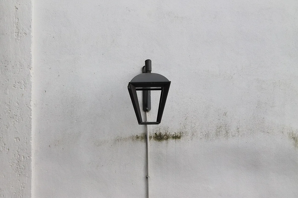 Black street lantern mounted on a pale wall in Porto