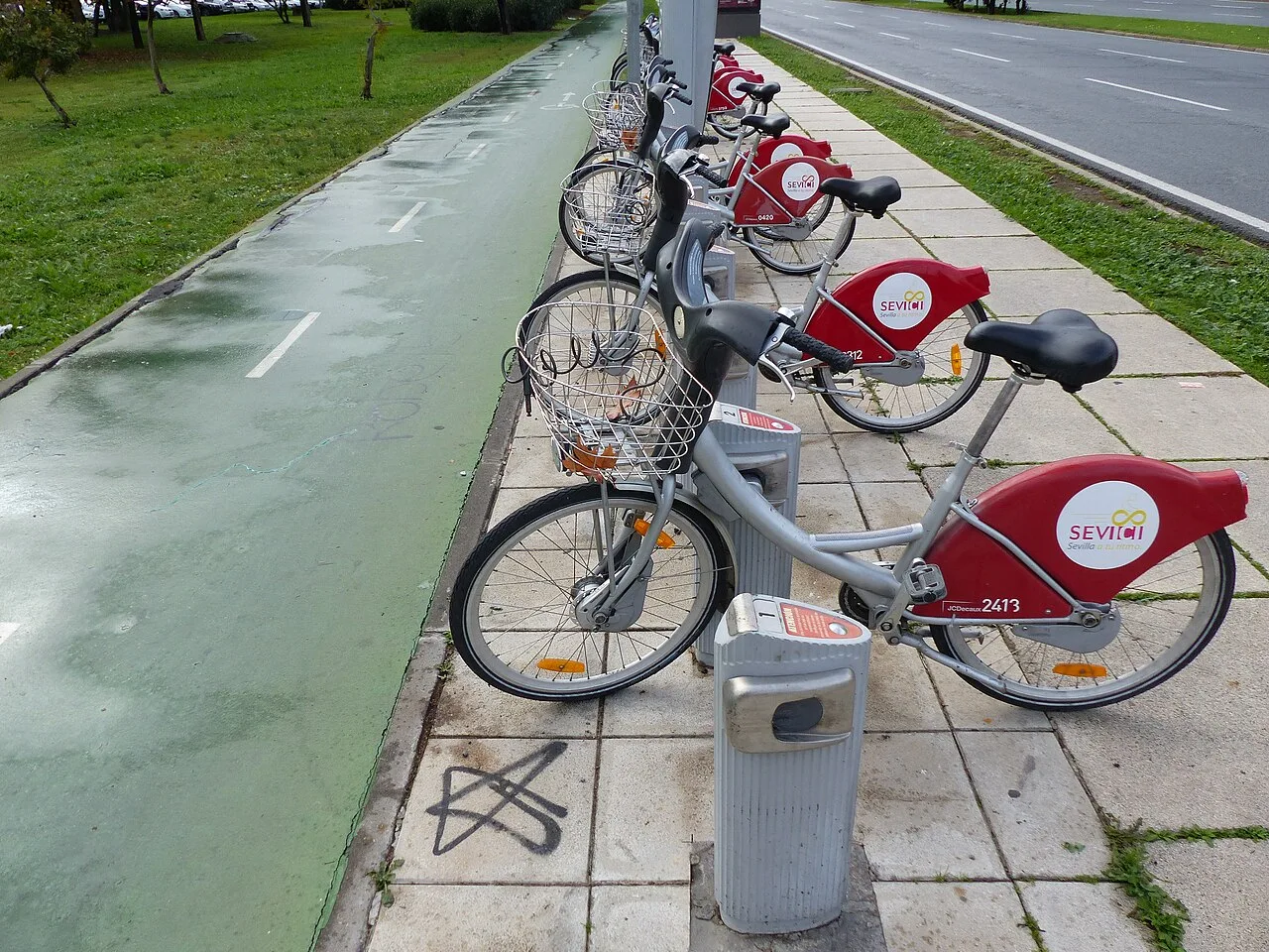 Sevici bicycles docked beside a marked cycle lane in Sevilla Este